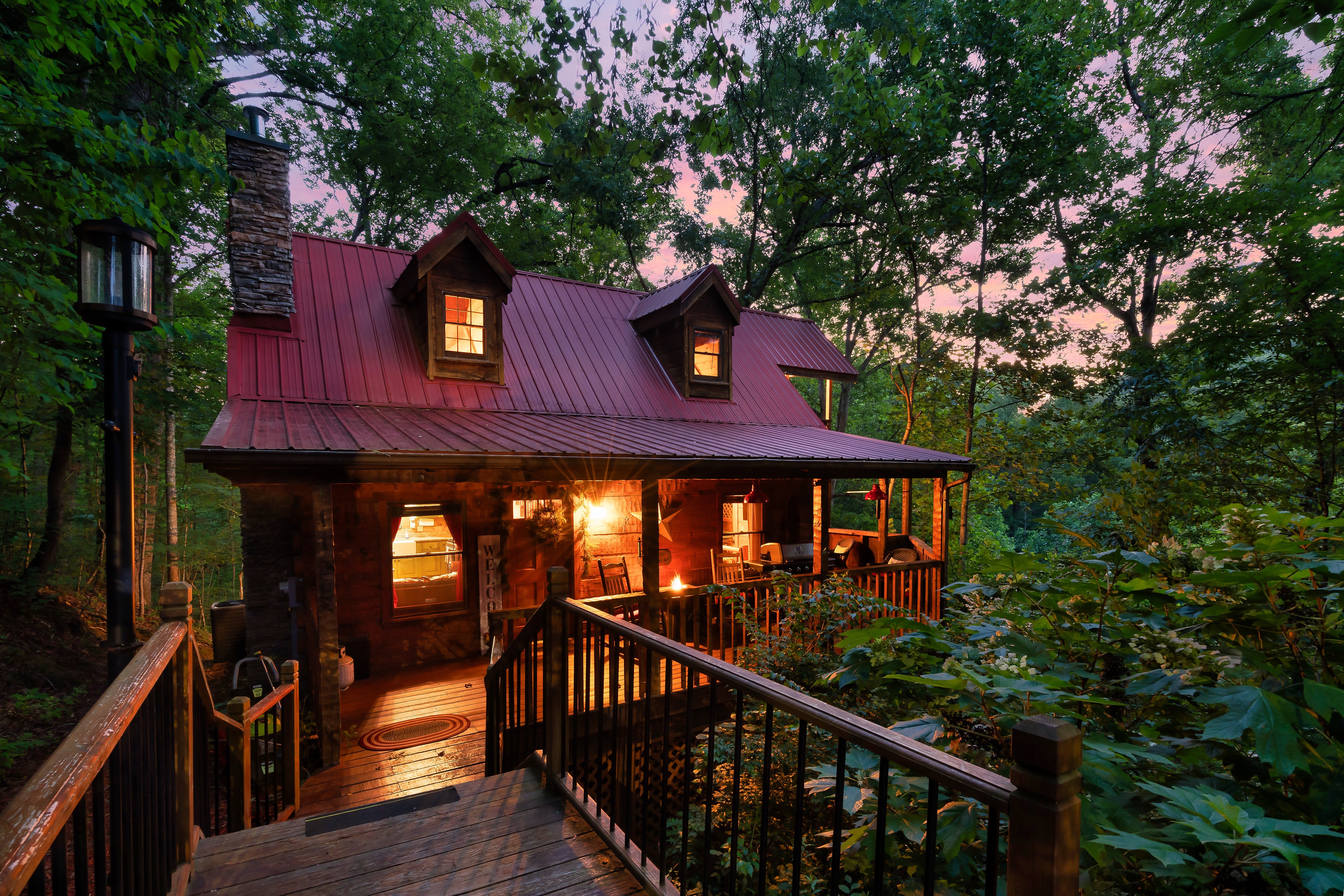Rustic Rooster log cabin at twilight with red metal roof in Sevierville Tennessee
