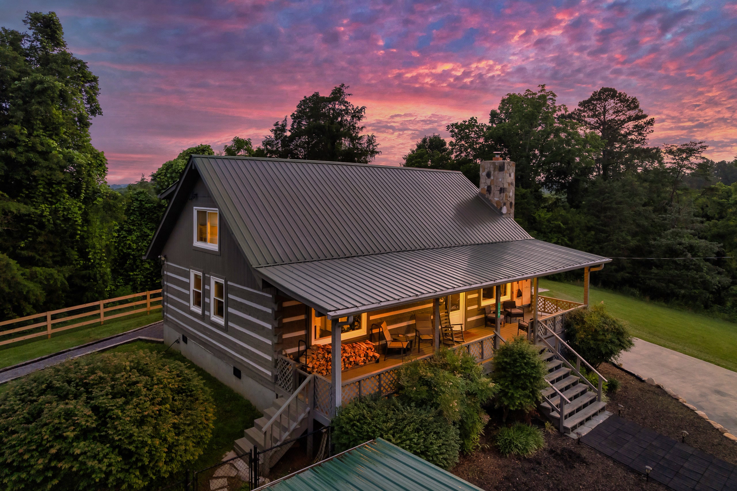Hillside Haven aerial view of cabin with metal roof and wraparound porch at sunset