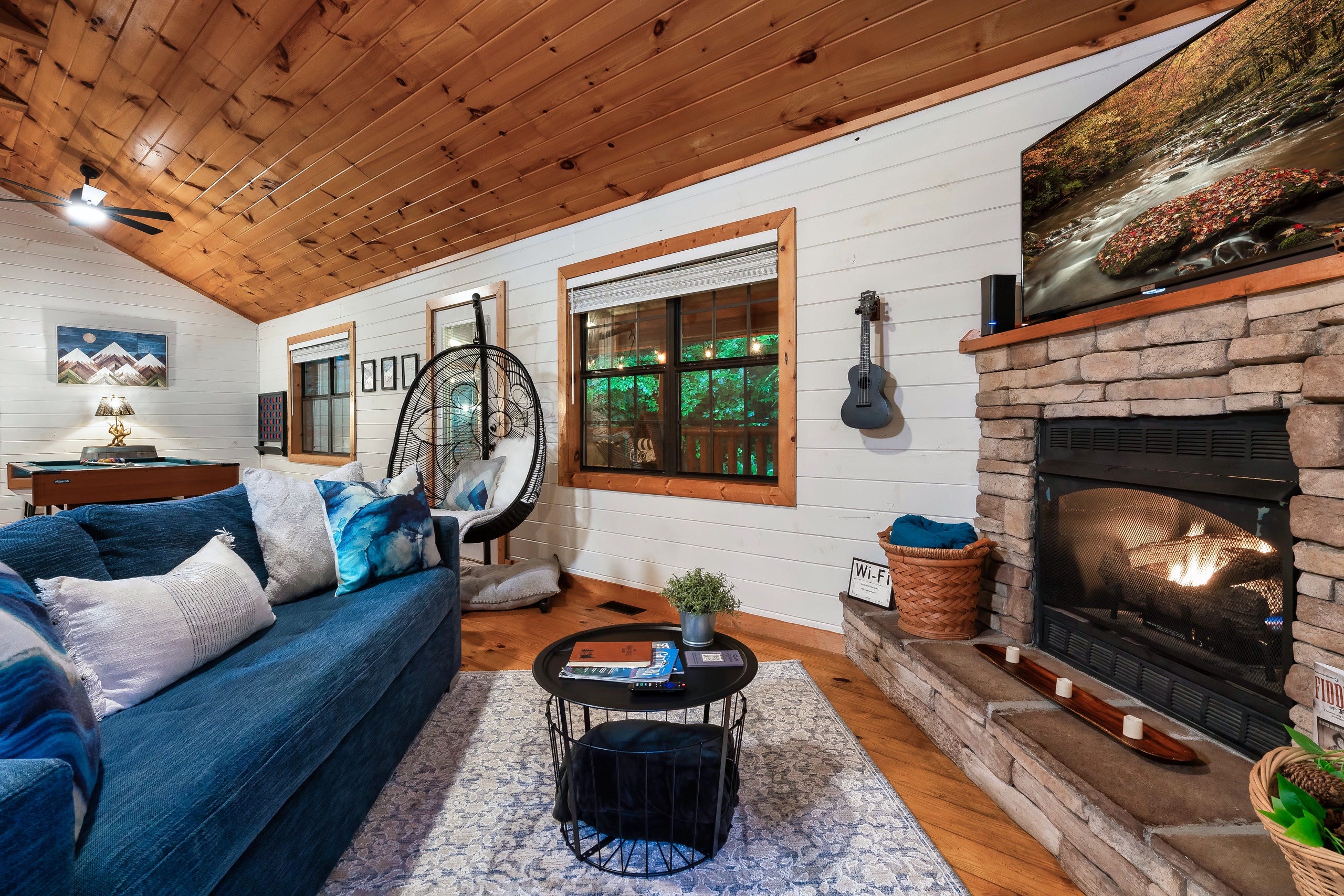 Smoky Creek Hideaway living room with teal sofa, stone fireplace, and hanging bubble chair