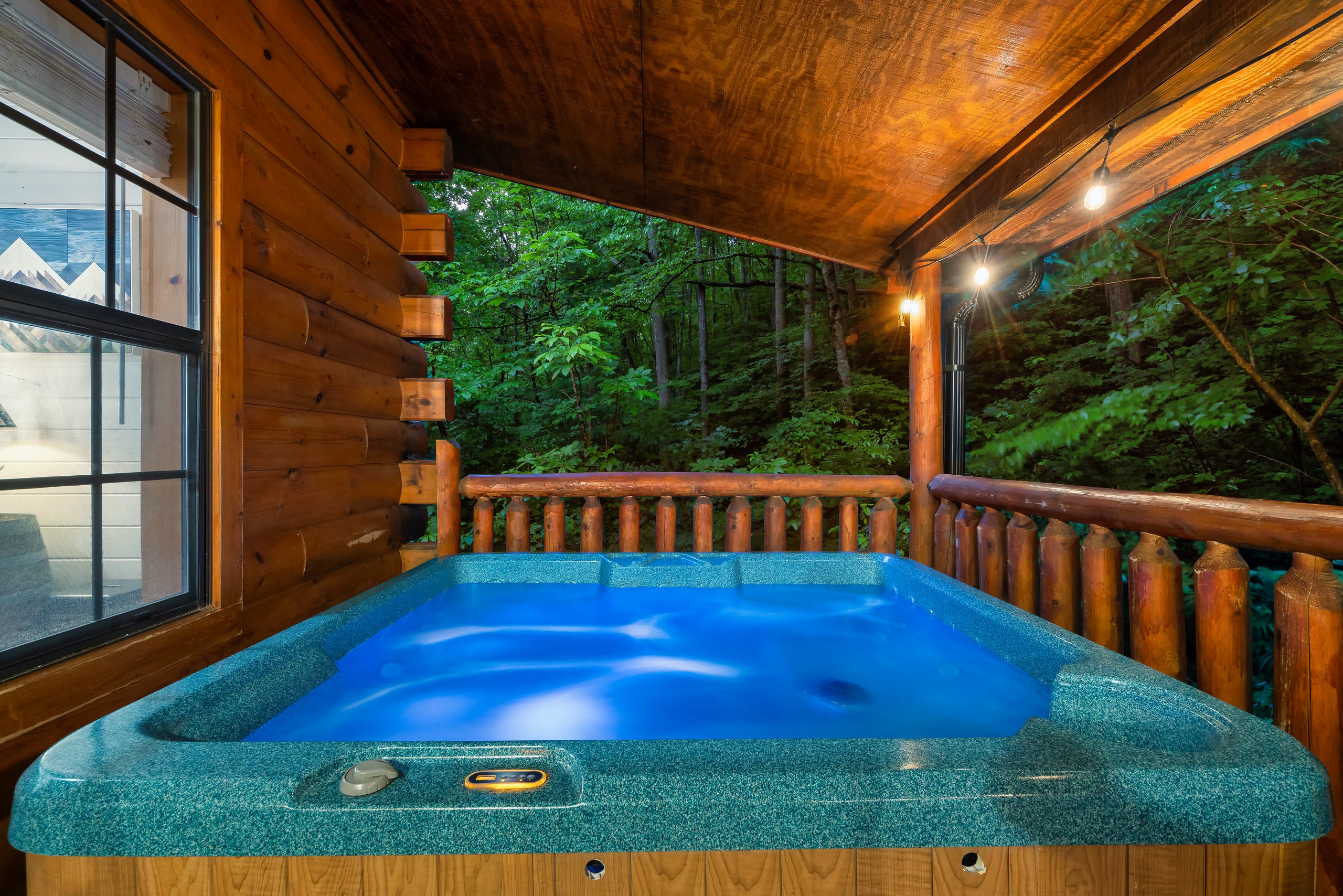 Turquoise hot tub on covered deck overlooking Smoky Mountains forest at dusk