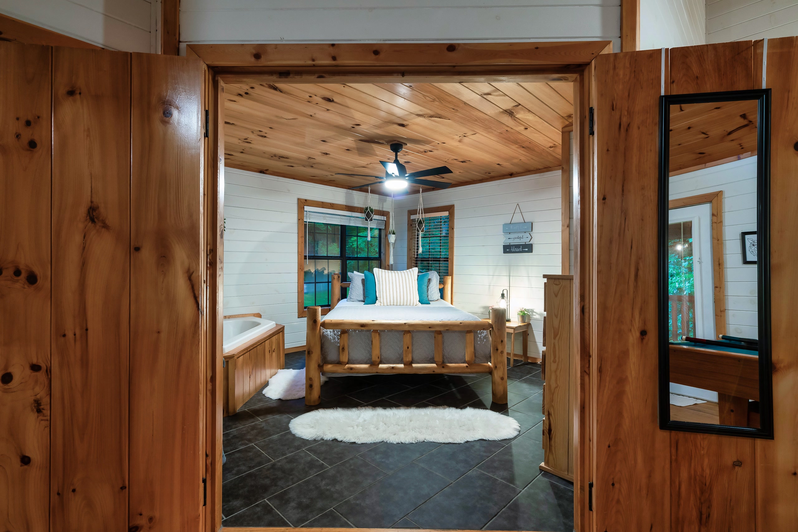 Smoky Creek Hideaway master bedroom with log bed and jetted tub through doorway