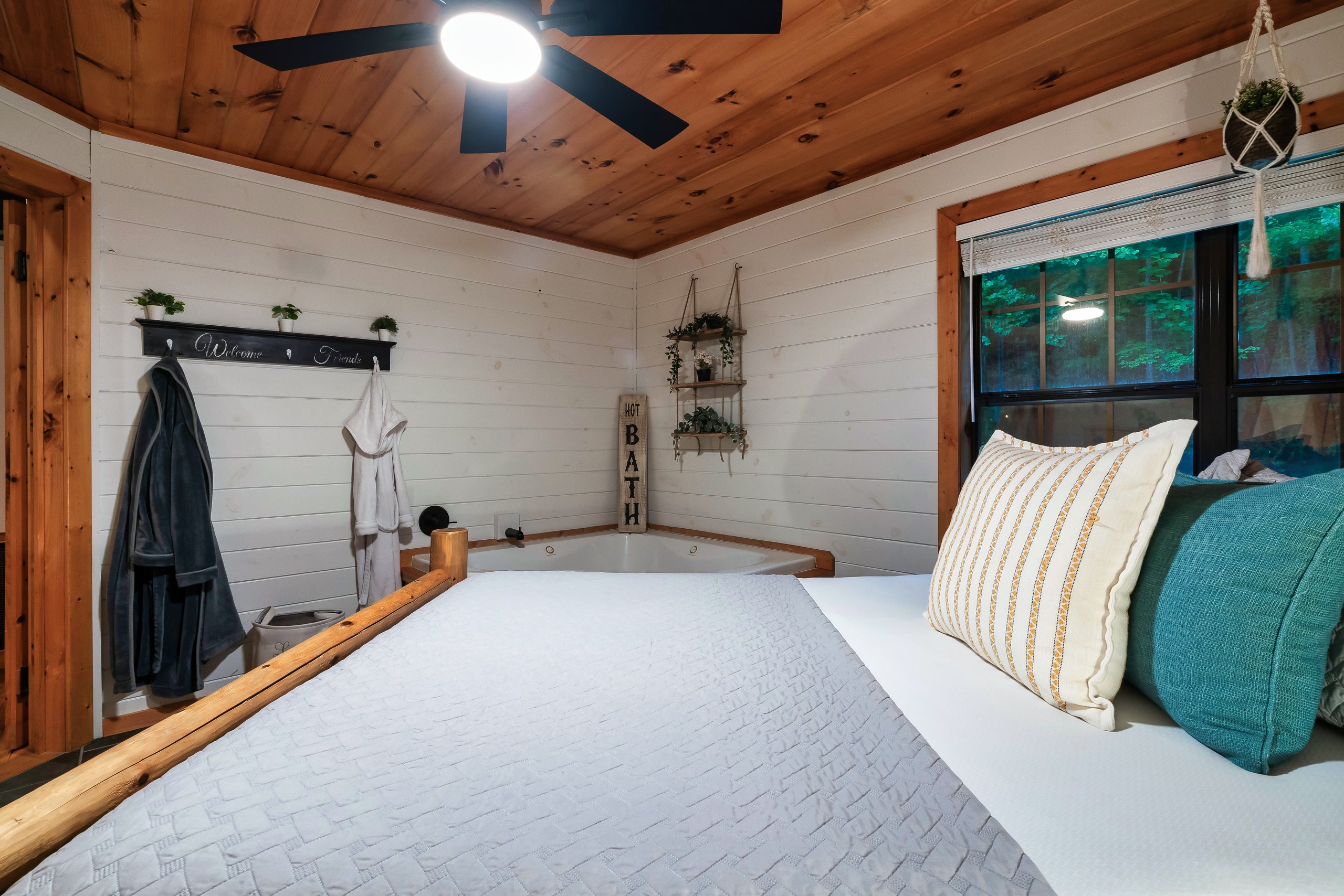 Rustic bedroom with white bedding, teal accents, and corner jetted tub in Tennessee