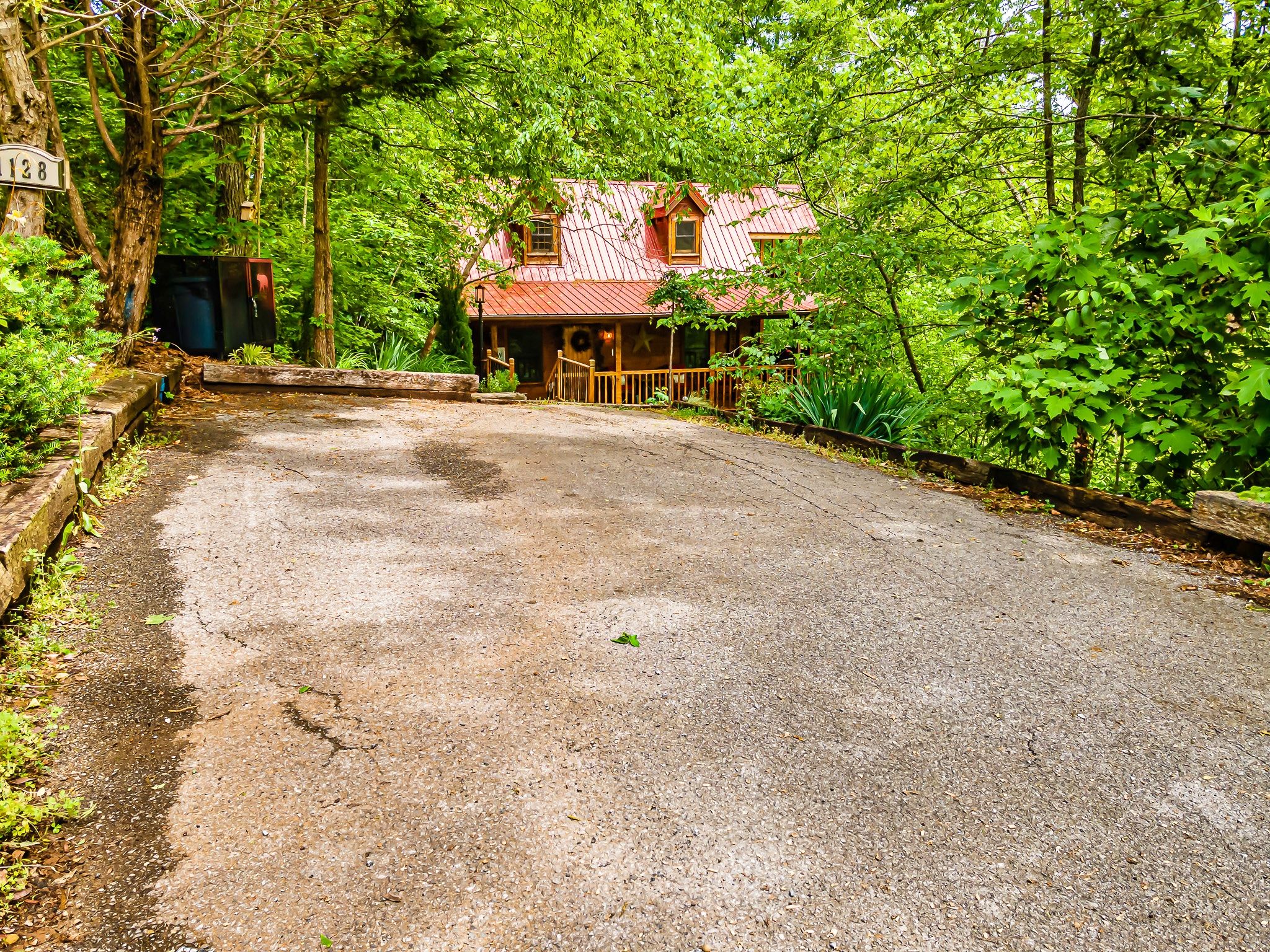 Rustic Rooster cabin driveway approach with red metal roof in Tennessee forest