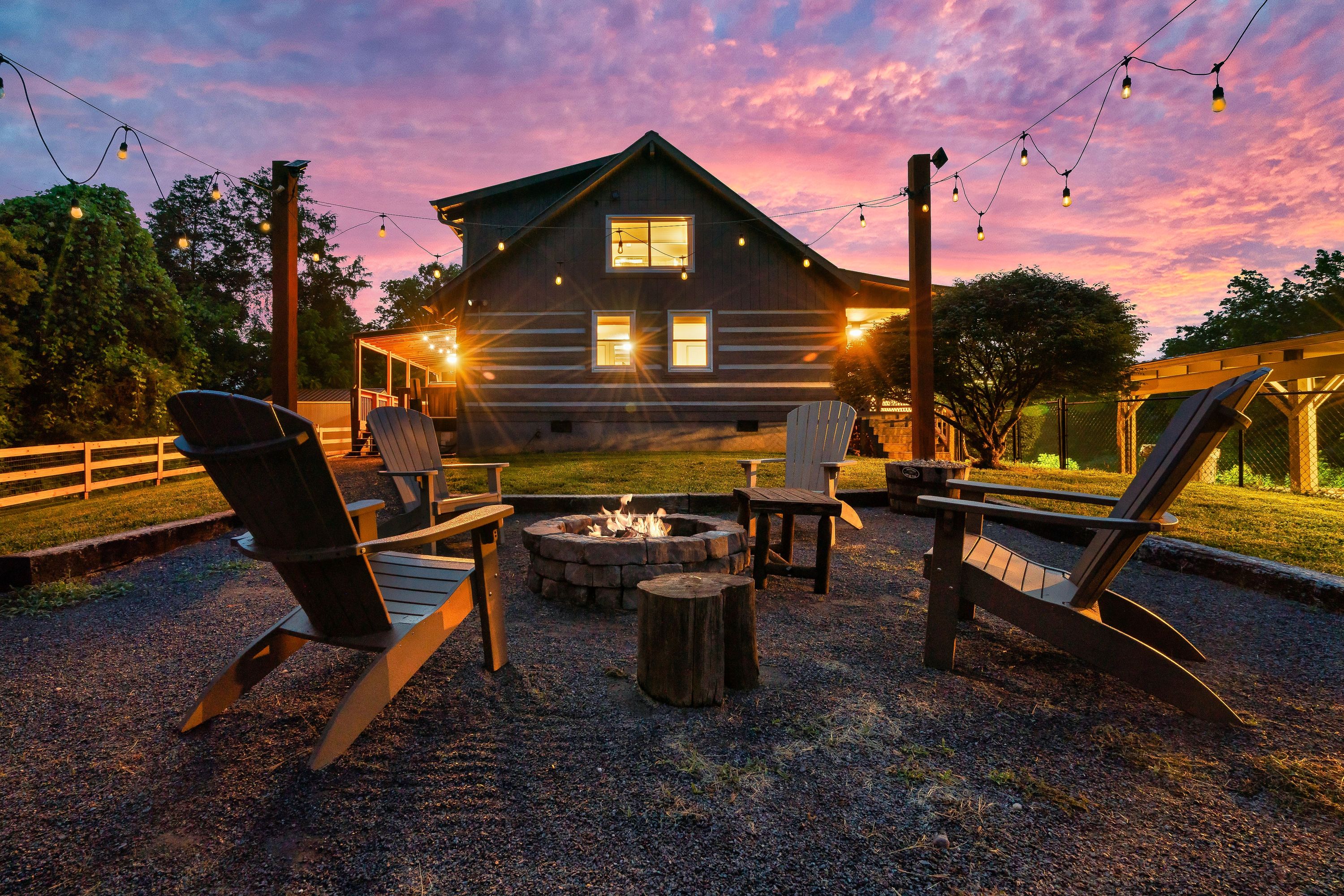 Cabin with fire pit and string lights at sunset